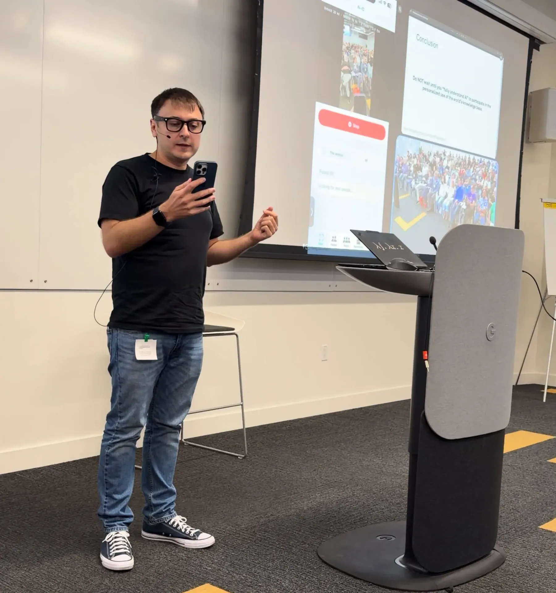 Oleg Sotnikov on stage at a Google Gemini event at Google's Sunnyvale campus, demoing a custom Ray-Ban Meta glasses setup with streaming face recognition on iPhone for better networking